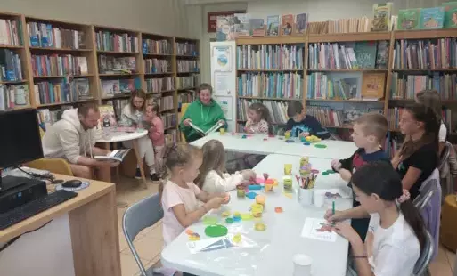 Na zdjęciu dzieci z rodzicami bawiące się klockami lego, ciastoliną, czytające książki.